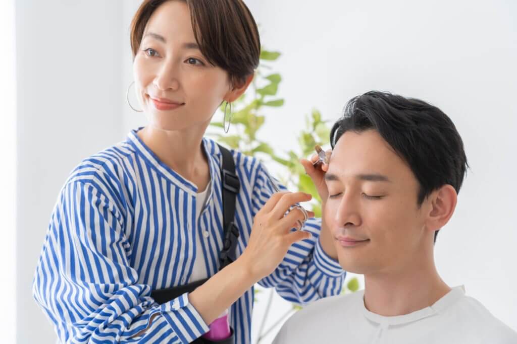 眉毛を整える美容師と日本人男性